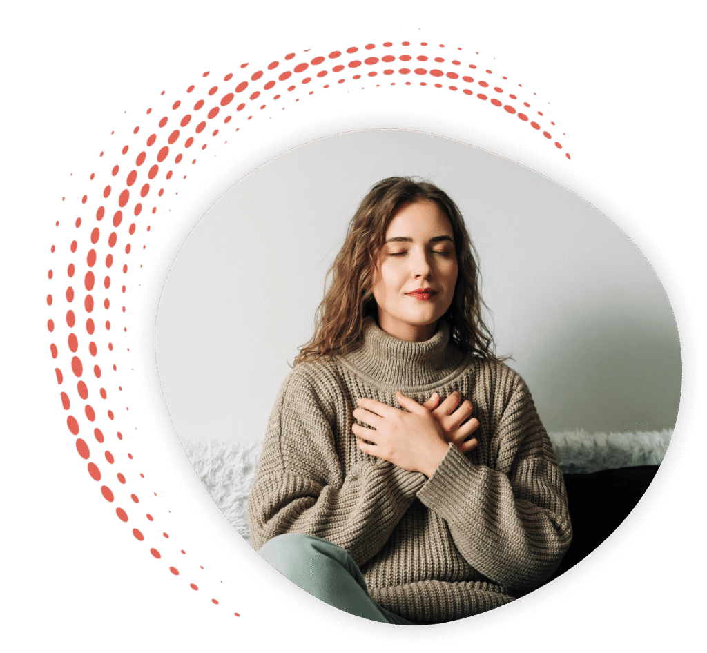 Woman sitting on a couch with her eyes closed and hands folded over her heart embracing Spiritually Integrated Psychotherapy​.